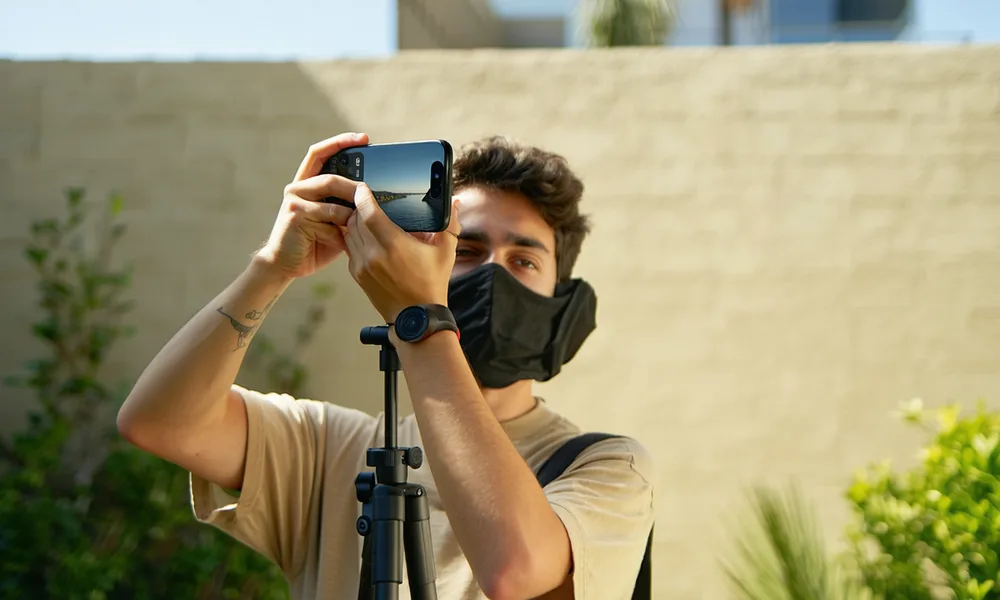 An independent video creator filming content with a smartphone in an outdoor setting